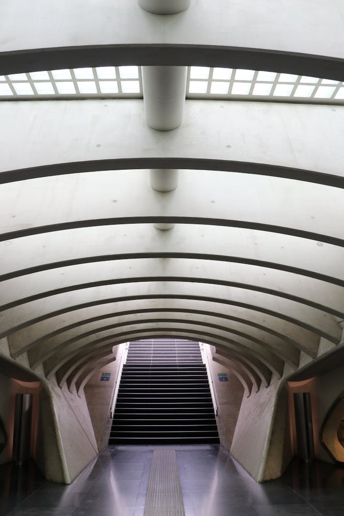 Interior view of a modern subway tunnel with curved concrete design and ascending stairs.